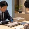 鮮やかなブルーを特徴とする無銘の高級腕時計を査定する日本人査定士と所有者