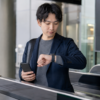 スマートフォンとスマートウォッチの連携を確認しながら駅を利用する日本人