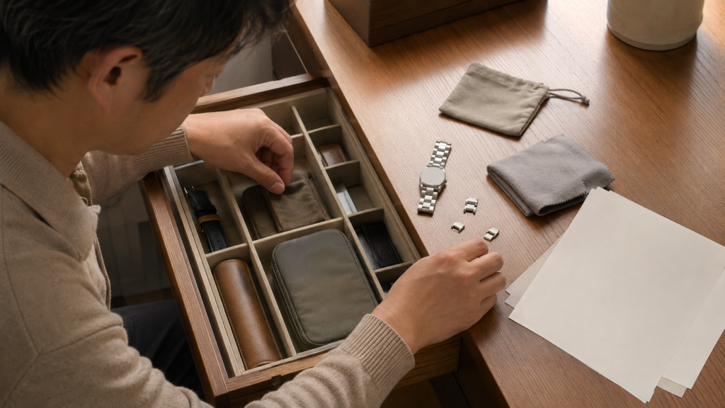 査定前にほかの付属品を探すをイメージした、腕時計の付属品を丁寧に整える手元